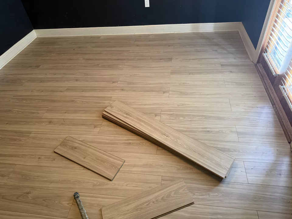 The same room with light oak-toned plank flooring installed wall to wall against the navy walls and white baseboard.